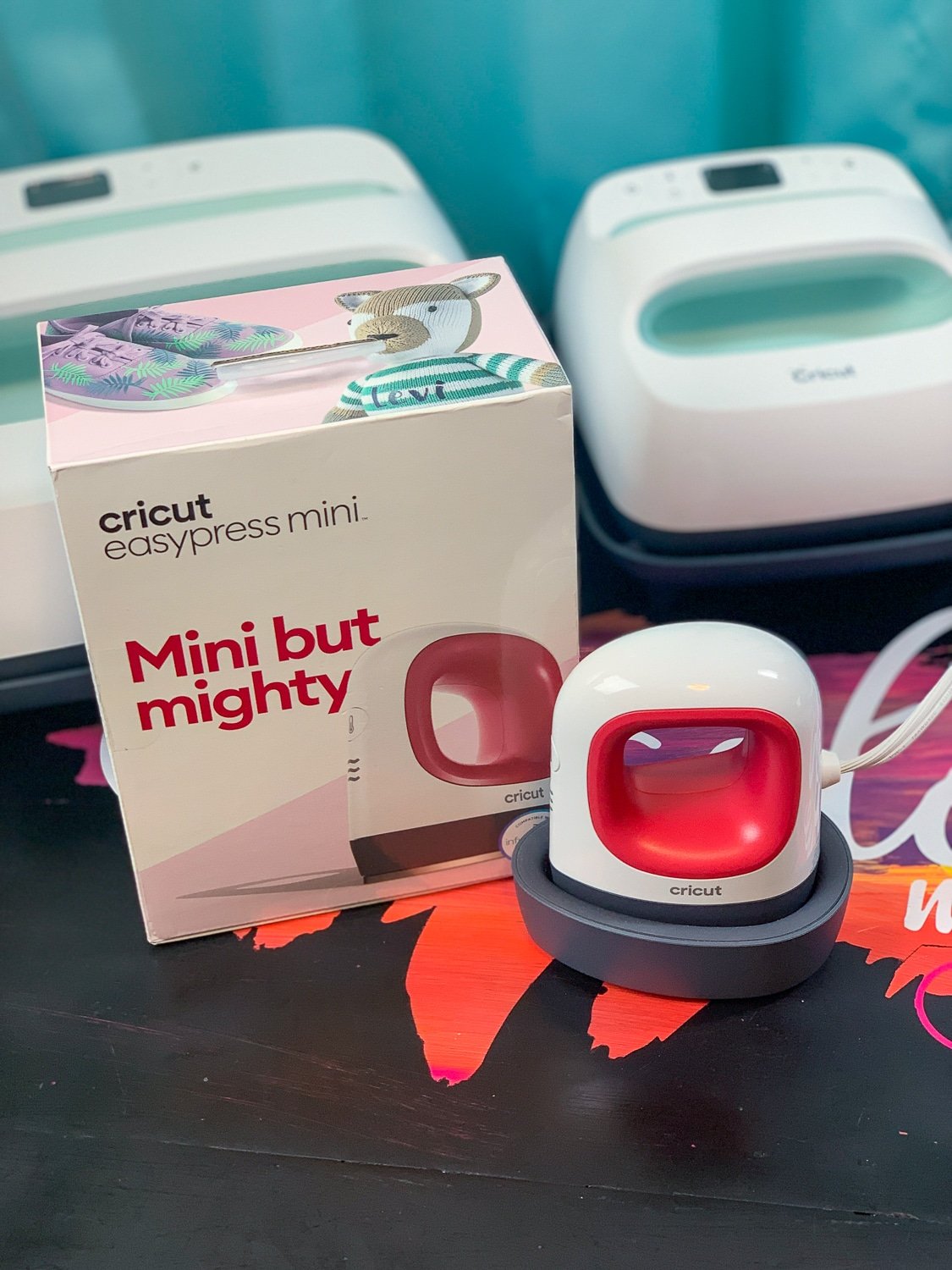 An image of the Cricut EasyPress Mini outside of the box, beside its original box.