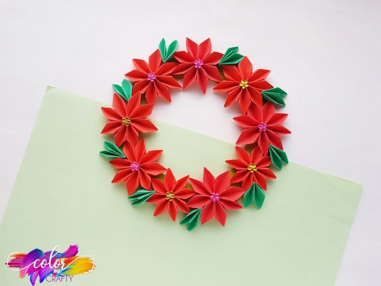 paper flower with red petals, green leaves, and colored dots in the center of the flowers