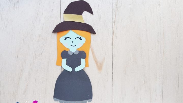smiling paper witch with a black hat and black dress