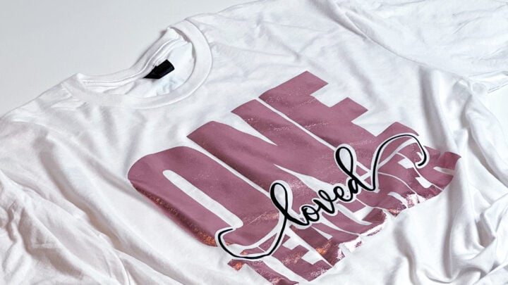 White t-shirt displaying a professional vinyl Cricut design with 'ONE loved TEACHER' in pink and black.