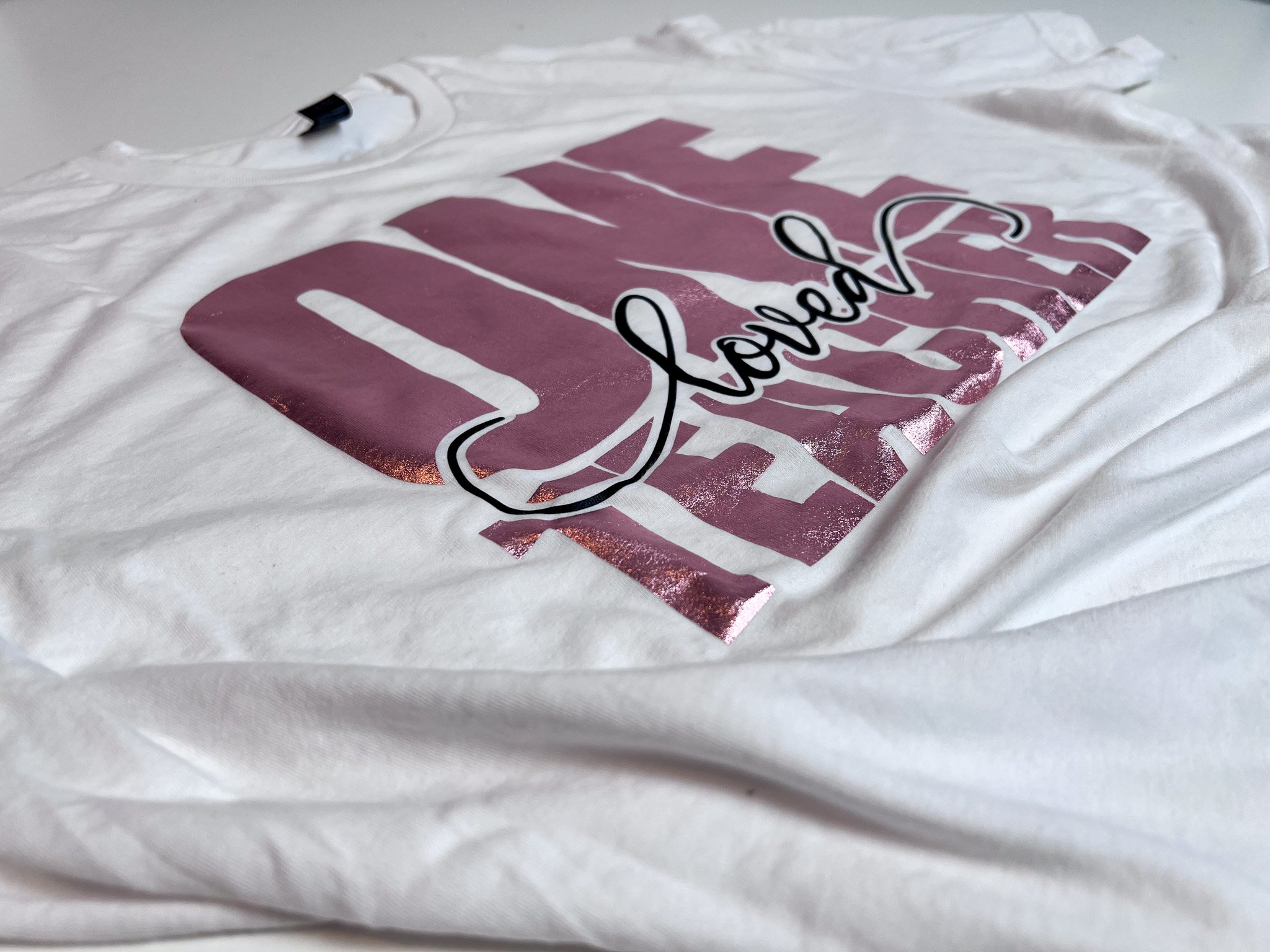 Close-up angled view of a custom t-shirt design made in Cricut Design Space, with pink and black vinyl layers.