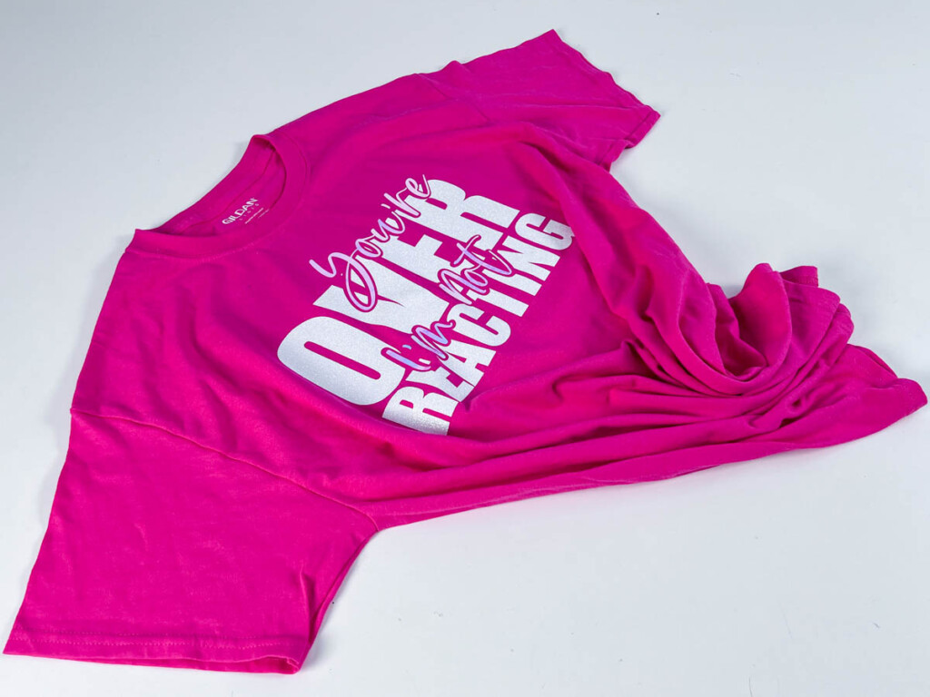 DIY Cricut t-shirt on a white background featuring a layered white vinyl design that says “You’re Overreacting I’m not,” created using a Cricut Joy and SVG made in Adobe Illustrator.